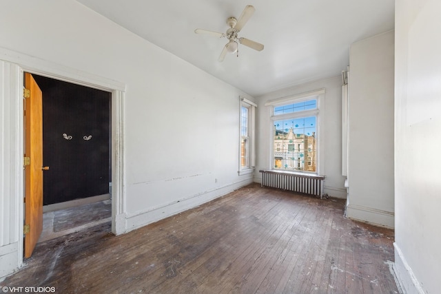 unfurnished room featuring hardwood / wood-style floors, radiator heating unit, a ceiling fan, and baseboards