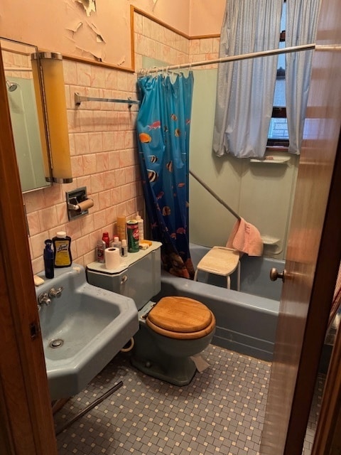 full bathroom featuring shower / bath combination with curtain, sink, decorative backsplash, toilet, and tile walls