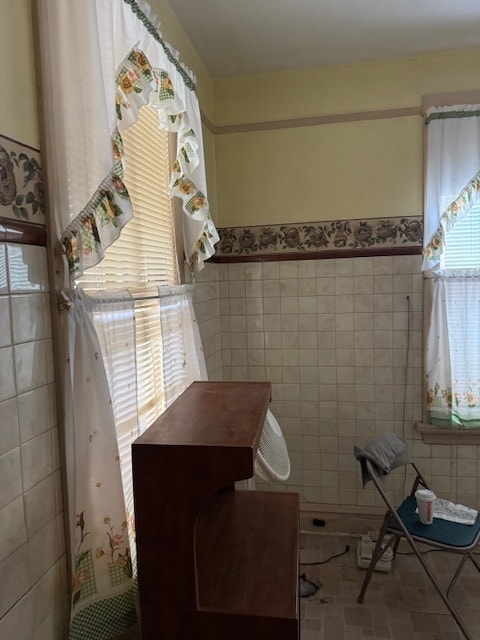 bathroom with plenty of natural light and tile walls