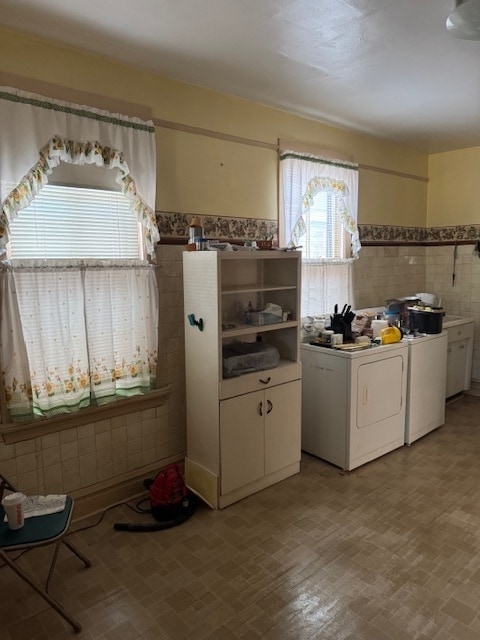 kitchen with white cabinets, washing machine and dryer, and tile walls