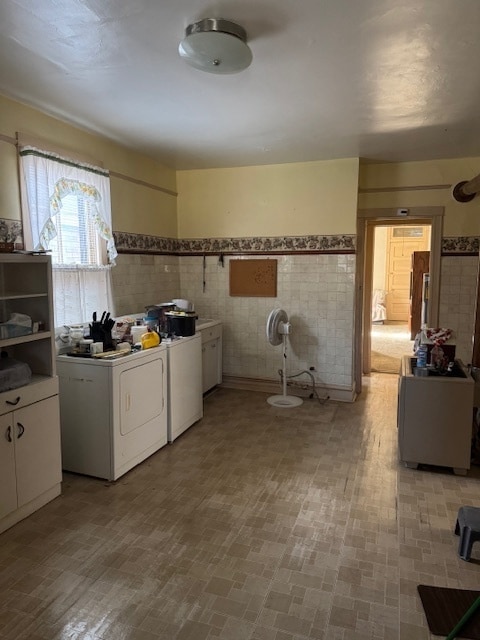 clothes washing area featuring washer and clothes dryer, cabinets, and tile walls