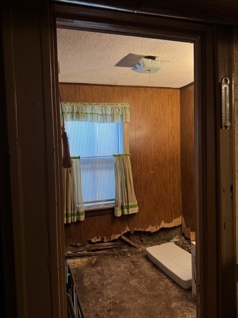 bathroom featuring a textured ceiling and wood walls