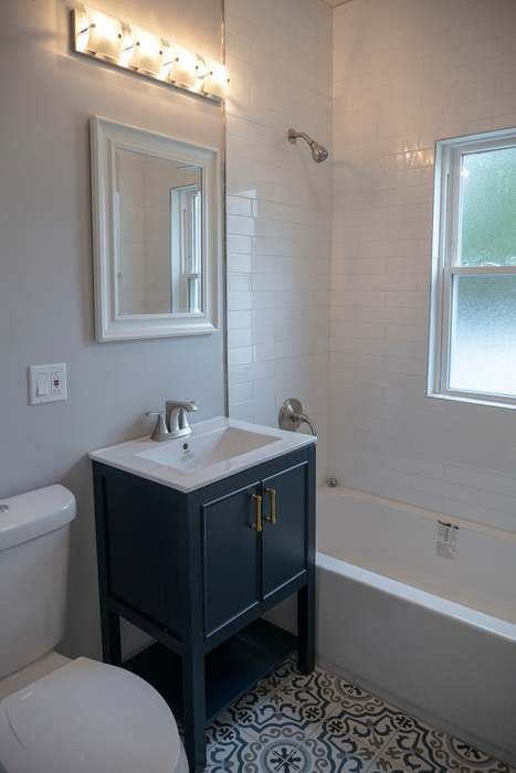 full bathroom with toilet, vanity, and tiled shower / bath combo