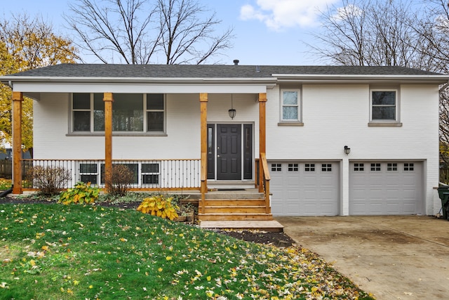 split foyer home with covered porch, a garage, and a front yard