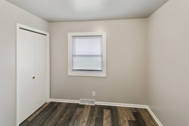 unfurnished bedroom featuring a closet and dark wood-type flooring