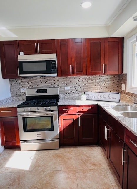 kitchen featuring light stone countertops, backsplash, crown molding, sink, and stainless steel gas stove