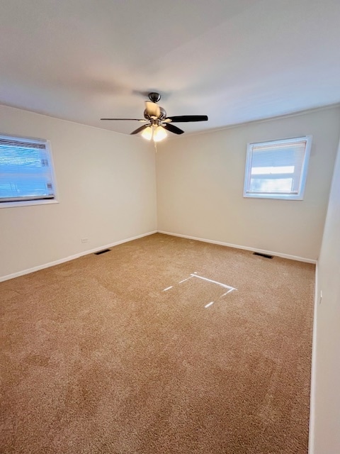 carpeted spare room featuring ceiling fan and a healthy amount of sunlight