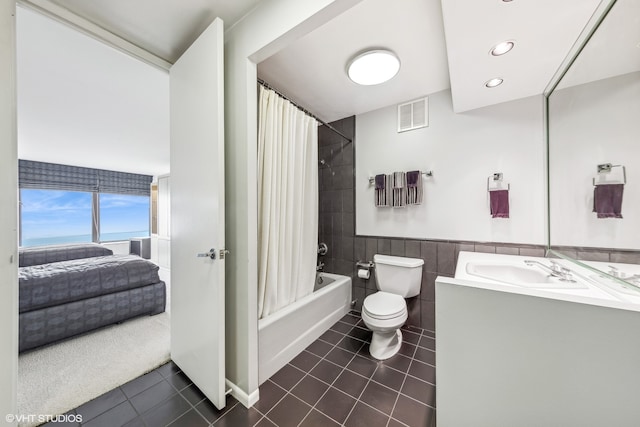 full bathroom featuring toilet, shower / bath combination with curtain, tile patterned floors, and tile walls