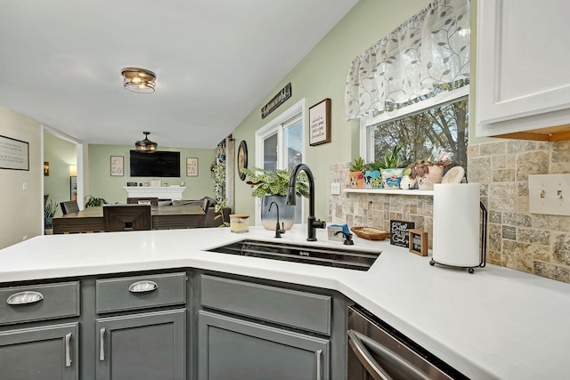 kitchen featuring gray cabinetry, backsplash, sink, stainless steel dishwasher, and white cabinetry