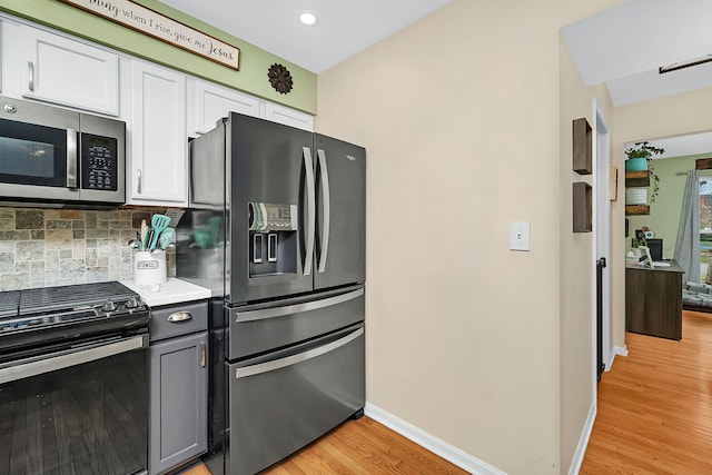 kitchen with backsplash, light hardwood / wood-style flooring, gray cabinets, appliances with stainless steel finishes, and white cabinetry