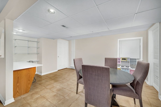 tiled dining space featuring a paneled ceiling