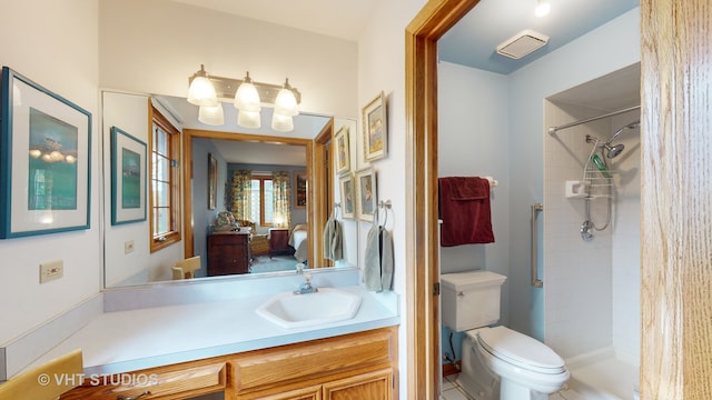 bathroom featuring a tile shower, vanity, and toilet