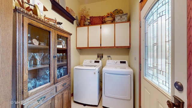 clothes washing area featuring cabinets, washer and dryer, and light tile patterned flooring