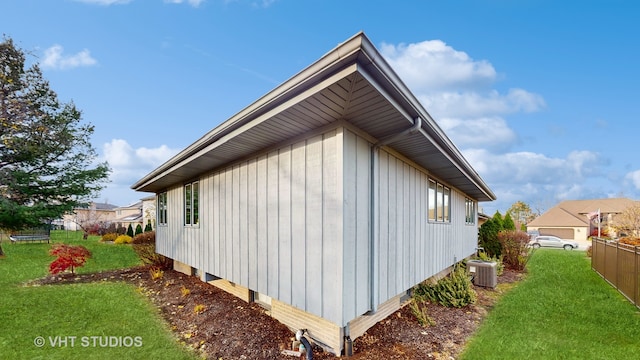 view of side of property featuring central air condition unit and a yard