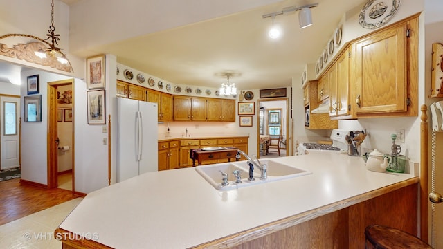 kitchen with white appliances, sink, light hardwood / wood-style flooring, decorative light fixtures, and kitchen peninsula