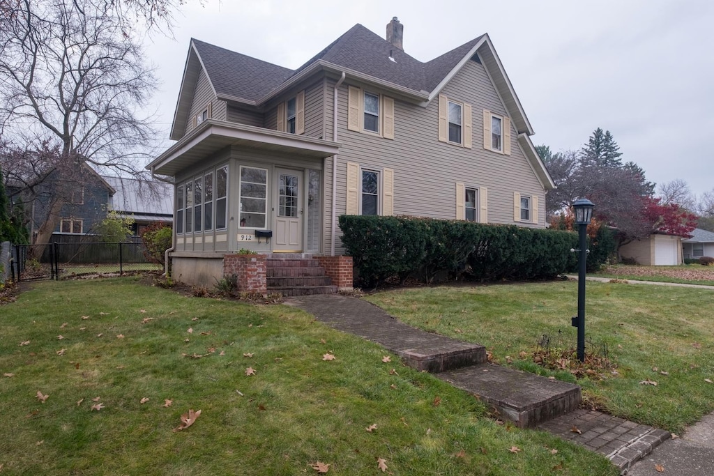 view of front facade with a sunroom and a front lawn