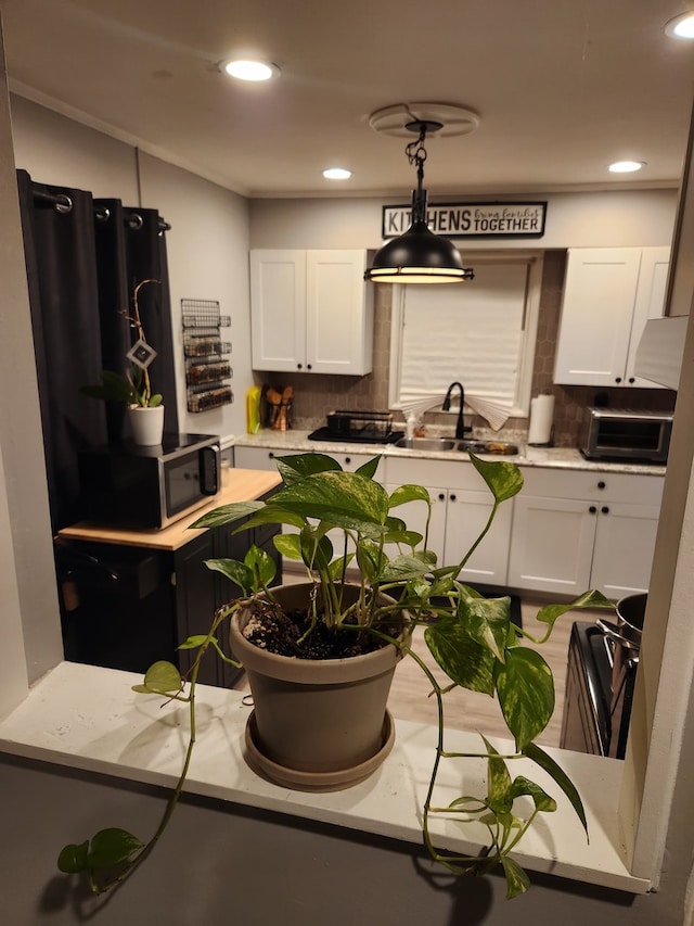 kitchen with decorative backsplash, white cabinetry, sink, and decorative light fixtures