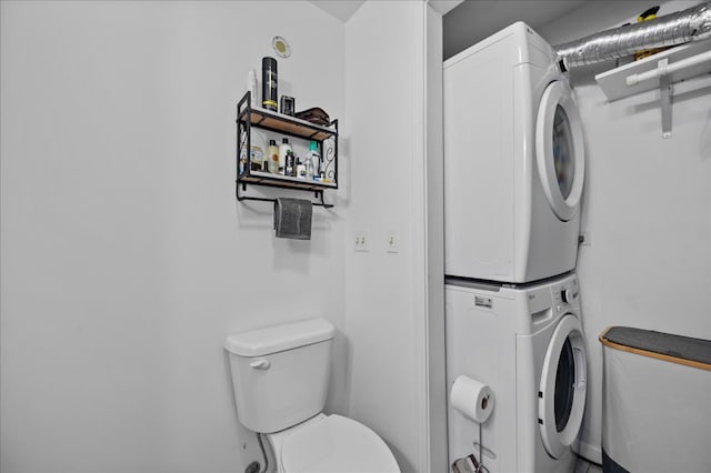 bathroom featuring toilet and stacked washer and clothes dryer