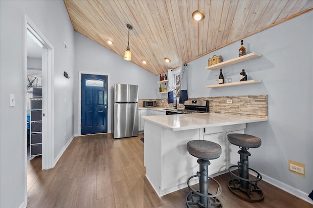 kitchen with a kitchen bar, stainless steel appliances, pendant lighting, wooden ceiling, and white cabinetry