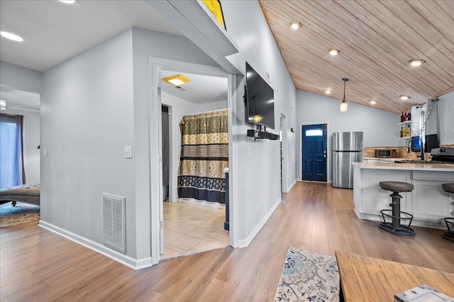 kitchen with stainless steel fridge, light wood-type flooring, wood ceiling, white cabinetry, and hanging light fixtures