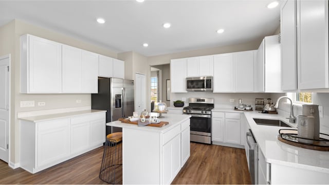 kitchen with sink, stainless steel appliances, a kitchen island, dark hardwood / wood-style floors, and white cabinets