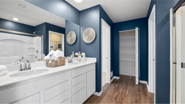 bathroom with hardwood / wood-style floors, vanity, and a shower with door