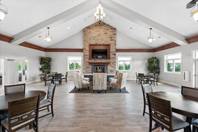 dining space with beam ceiling, light hardwood / wood-style floors, a fireplace, and a wealth of natural light