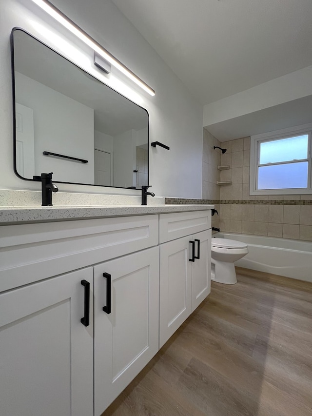 full bathroom featuring toilet, hardwood / wood-style floors, vanity, and tiled shower / bath combo