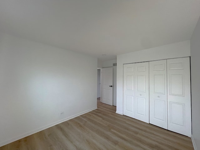 unfurnished bedroom featuring light hardwood / wood-style floors and a closet