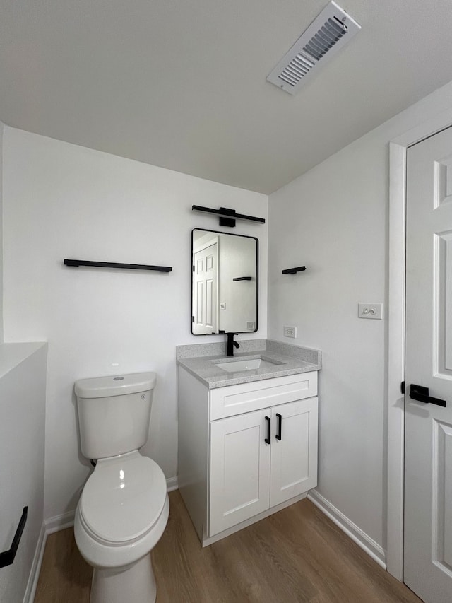 bathroom featuring vanity, wood-type flooring, and toilet