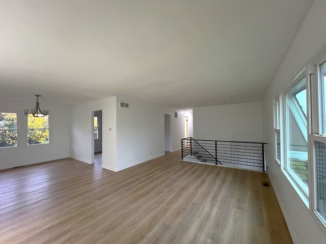 unfurnished living room with a notable chandelier and light wood-type flooring