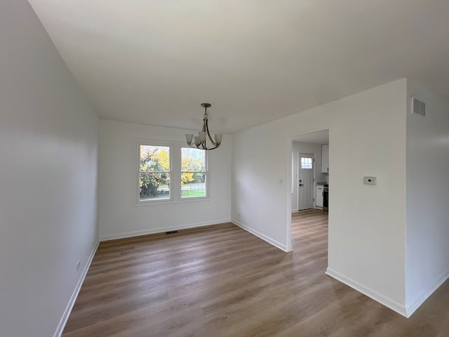 unfurnished dining area with hardwood / wood-style floors and an inviting chandelier