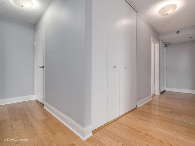 corridor featuring a textured ceiling and light wood-type flooring