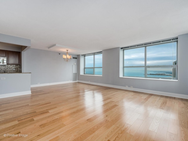 unfurnished living room with light hardwood / wood-style flooring and a chandelier