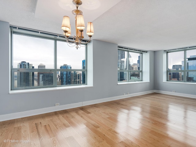 empty room featuring a chandelier, a textured ceiling, and hardwood / wood-style flooring