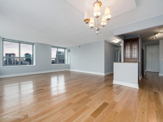 unfurnished living room featuring a chandelier and light hardwood / wood-style floors