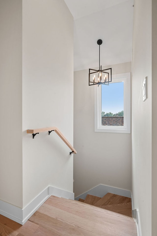 staircase with wood-type flooring and a notable chandelier