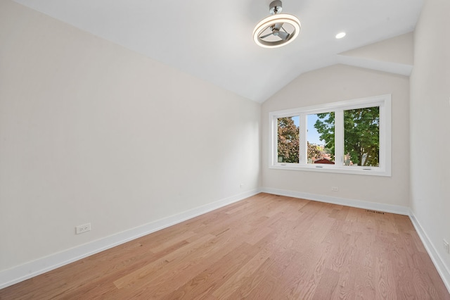 spare room with light hardwood / wood-style flooring and vaulted ceiling