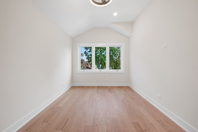 spare room featuring lofted ceiling and light hardwood / wood-style flooring