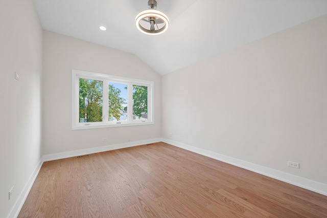 spare room featuring light wood-type flooring and lofted ceiling