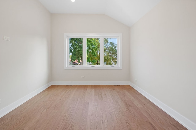 unfurnished room with lofted ceiling and light wood-type flooring