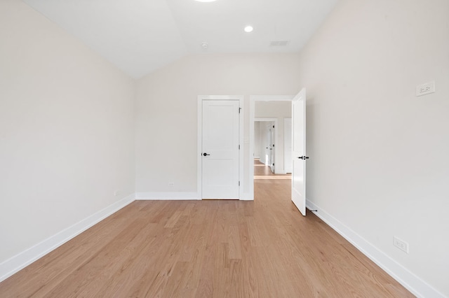 spare room featuring light hardwood / wood-style floors and lofted ceiling