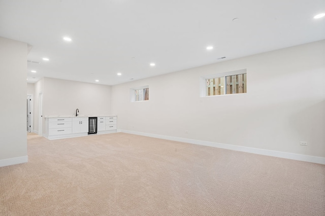 basement with light colored carpet, sink, and a wealth of natural light