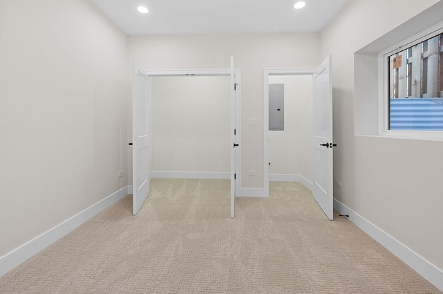 unfurnished bedroom with light carpet, electric panel, and a closet