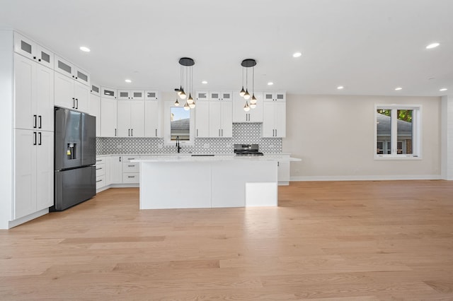 kitchen with white cabinetry, hanging light fixtures, light hardwood / wood-style floors, a kitchen island, and appliances with stainless steel finishes