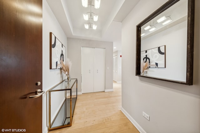 corridor featuring light wood-type flooring and a chandelier