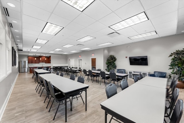 dining space with a drop ceiling and light hardwood / wood-style flooring