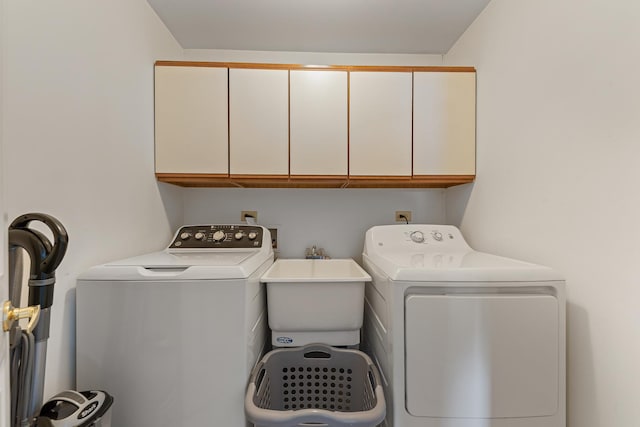 clothes washing area with washer and clothes dryer, cabinets, and sink