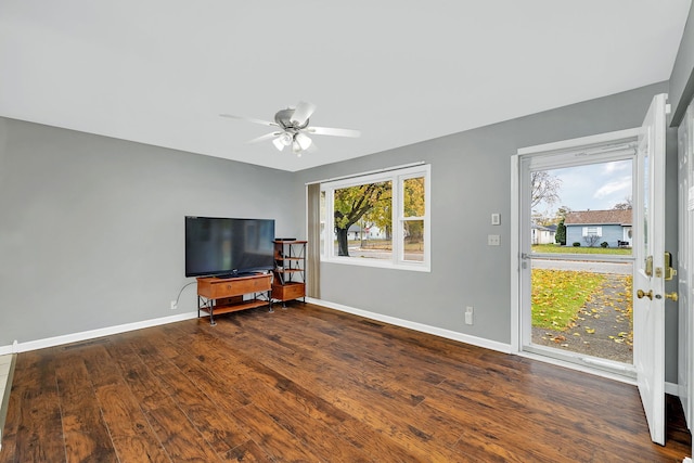 unfurnished living room featuring ceiling fan and dark wood-type flooring