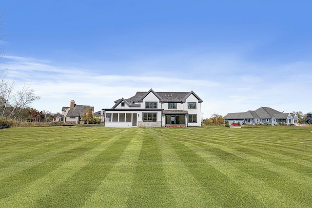 rear view of property with a sunroom and a lawn